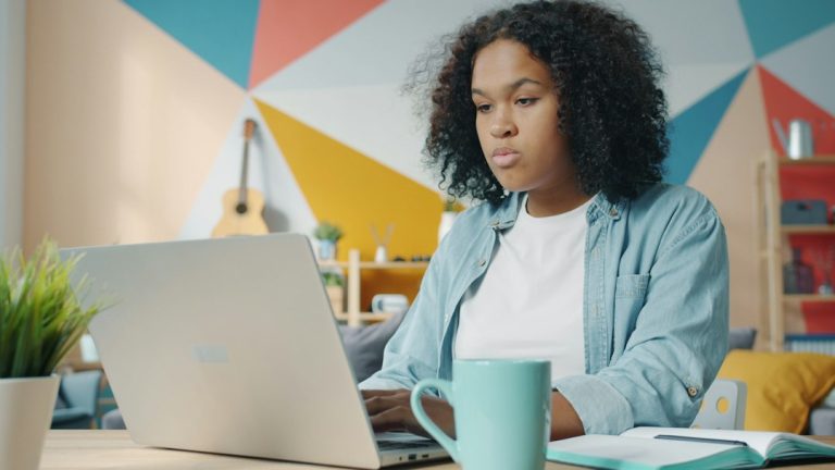 Adult learner using a laptop and taking notes for flexible online study